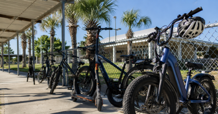 E-bikes and electric scooters parked outside a Florida public school with a helmet on the handlebars