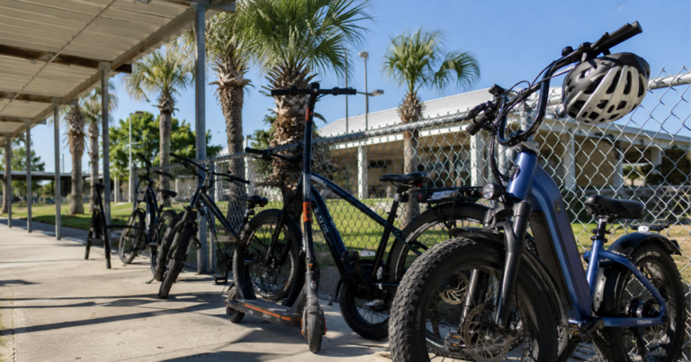 E-bikes and electric scooters parked outside a Florida public school with a helmet on the handlebars